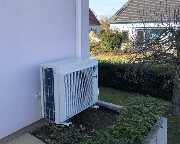Extérieur d'habitation avec climatiseur split monté sur mur de briques rouges